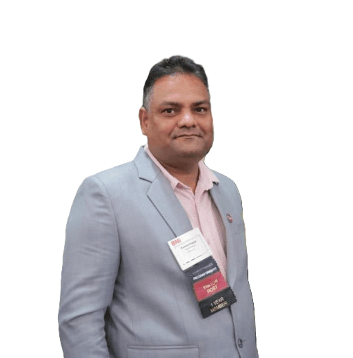 Individual wearing a light gray suit with a pink shirt, adorned with multiple conference name badges.